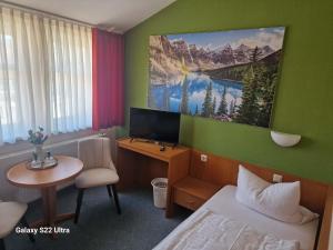 a hotel room with a bed and a desk with a television at Hotel Restaurant Yiamas in Breitenworbis