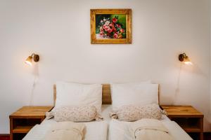 a bed with two pillows and a picture on the wall at Hotel Elenka in Veľký Meder
