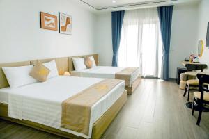 a hotel room with two beds and a table at Halo Motel Đồ Sơn in Ðố Sơn
