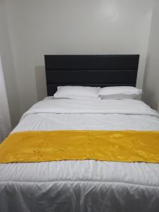 a large white bed with a yellow blanket on it at Zariah Homes 1 in Kakamega