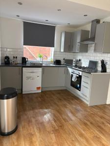 a kitchen with white appliances and a wooden floor at Cosy 3 Bed house with garden 5 min walk from Doncaster Racecourse in Doncaster