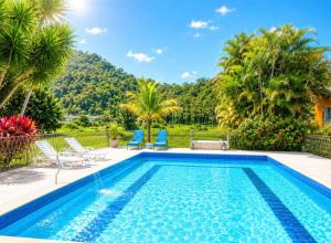 a swimming pool with two chairs and a villa at Pousada Jupter in Teresópolis