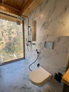 a bathroom with a toilet and a window at Tirthan Chalet in Kulu +40 photos