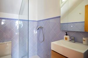 a blue tiled bathroom with a shower and a sink at Casa Emilia in Baeza