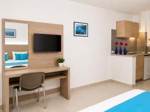 a room with a desk with a television and a bed at Vergina Sun in Faliraki