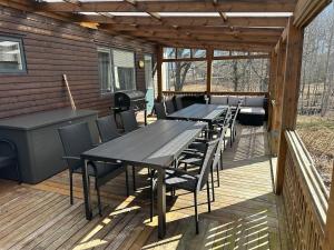 a deck with tables and chairs and a grill at Stor villa med jacuzzi in Herräng