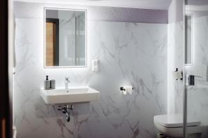 a white bathroom with a sink and a toilet at HarzHold - Apartmenthotel in Osterode +46 photos