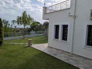 a white house with a balcony and a yard at Homezie AGRIA in Agria