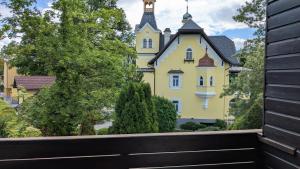 a yellow house with a black fence in front of it at Hotel Garni Vindobona in Pörtschach am Wörthersee
