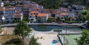 a city with a swimming pool in front of a town at Casa da Eira in Arganil