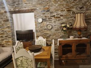 a living room with a table and a stone wall at Casa da Eira in Arganil