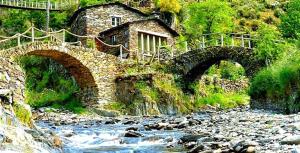 a stone bridge over a river with a house in the background at Casa da Eira in Arganil
