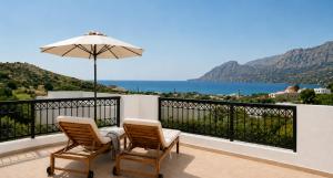a balcony with two chairs and an umbrella at Orama Studios in Plakias