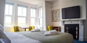 a bedroom with a bed with a fireplace and a flat screen tv at Tommy Jacks Beach Apartments in Bude