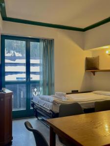 a room with two beds and a large window at Central SPORT CAMPIGLIO 407 in Madonna di Campiglio