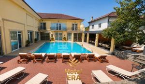 a swimming pool with lounge chairs and a house at Hotel ERA in Prishtinë