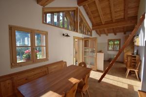 a dining room with a wooden table and windows at Chalet Brenta Dolomites in Madonna di Campiglio