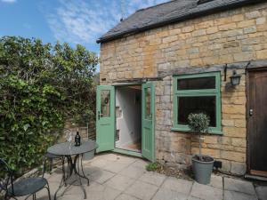 a brick house with a green door and a table at Wheelwright Cottage in Moreton in Marsh