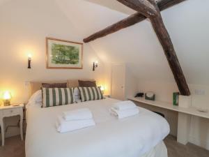 a bedroom with a white bed with two towels on it at Wheelwright Cottage in Moreton in Marsh