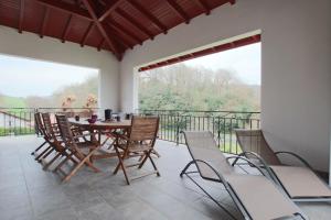 a dining room with a table and chairs on a balcony at Iduzki-alde bi in Souraïde