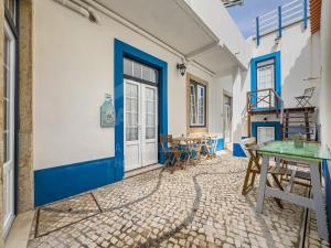a room with a blue door and tables and chairs at Casas da villa - Apartments in Ericeira