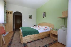 a bedroom with a wooden bed with a green blanket at Gästehaus Luise in Ossiach