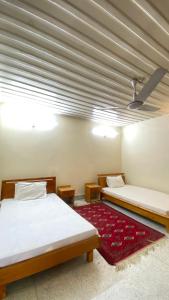 a room with two beds and a red rug at Comfort Inn in Chitral