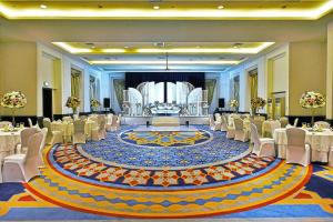 a large banquet hall with white chairs and a large rug at Bahi Ajman Palace Hotel in Ajman  +108 photos