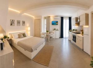 a large white bedroom with a bed and a kitchen at 18 Gradi Apartments in Birgi Vecchi