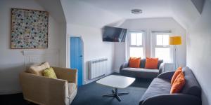 a living room with a couch and a chair at Tommy Jacks Beach Apartments in Bude