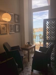 a living room with a table and chairs and a window at Door Nine -Townhouse with harbour views in Il-Furjana