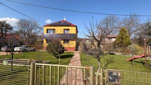 a yellow house with a fence in front of it at Loft Apartment with Parking in Poruba
