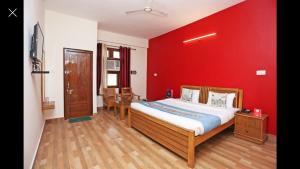 a bedroom with a red wall with a bed and chairs at hotel gsa & guest house in Haridwār