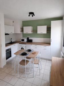 a kitchen with white cabinets and a wooden table and chairs at Studio avec terrasse et jardin privatif - Figeac centre - Parking gratuit in Figeac