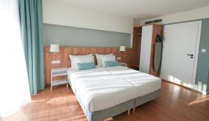 a bedroom with a large white bed with blue pillows at PINEA Resort in Pobierowo +122 photos