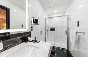 a white bathroom with a shower and a sink at Montcalm Royal London House, London City in London