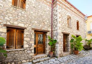 a stone building with wooden doors and potted plants at Limni Stone Apartments in Límni