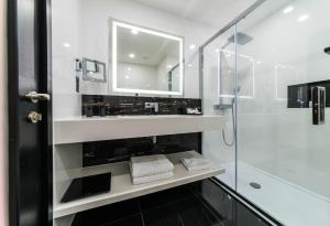 a bathroom with a shower and a sink and a mirror at Montcalm Royal London House, London City in London