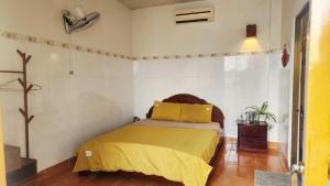 a bedroom with a bed with a yellow bedspread at Le Condor House and Café in Con Dao