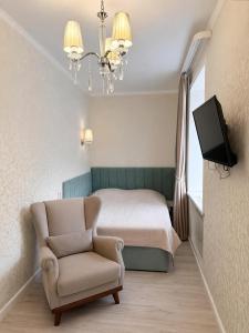 a bedroom with a bed and a chair and a television at Happy House in Karagandy