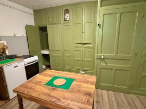 a kitchen with green cabinets and a wooden table at Chez le Sabotier, central et confortable in Rosières