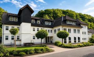 a large white house with a black roof at HarzHold - Apartmenthotel in Osterode