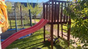a playground with a red slide in a yard at 3 Bedroom Apartment, Playground, bounce mat jump ring in Poruba