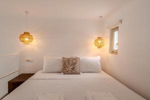 a white bedroom with a bed with two lamps at Jo&Co Mykonos Nature Suites N3 in Plintri