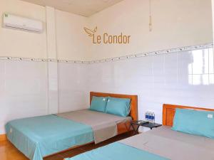 two beds in a room with a sign on the wall at Le Condor House and Café in Con Dao