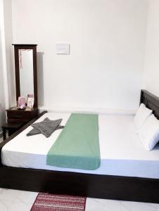 a bedroom with a bed with a green blanket on it at New Happy bay in Arugam Bay