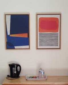 two framed pictures on a wall above a wooden table at Camping du Pas Del Fang in Sainte-Marie-la-Mer