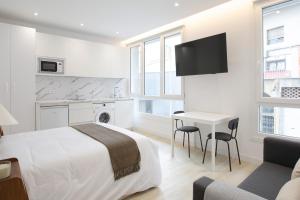 a white bedroom with a bed and a table with chairs at Urbil Puente Colgante in Portugalete