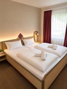 a bedroom with two beds with white sheets and a window at Hotel Panorama Nickenich in Nickenich