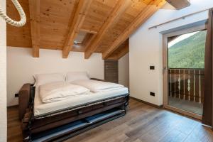 a bed in a room with a large window at ChaletMafi in Valdidentro